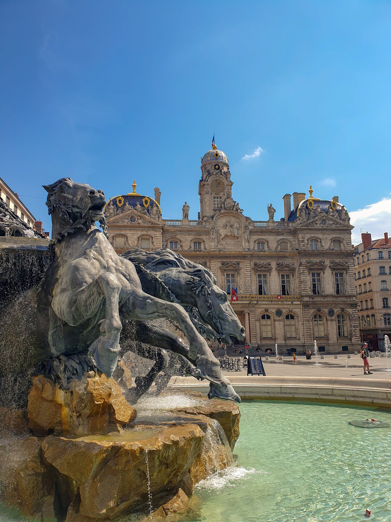 Photographie de la fontaine Bartholdi qui occupe le centre de la place des Terreaux, et qui fait face à l'hôtel de ville, situé à proximité du campus CPA de Lyon Grenoble.