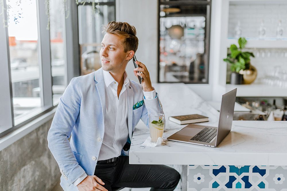 Photographie d'un homme qui est au téléphone, accoudé à une table dans un espace de travail.