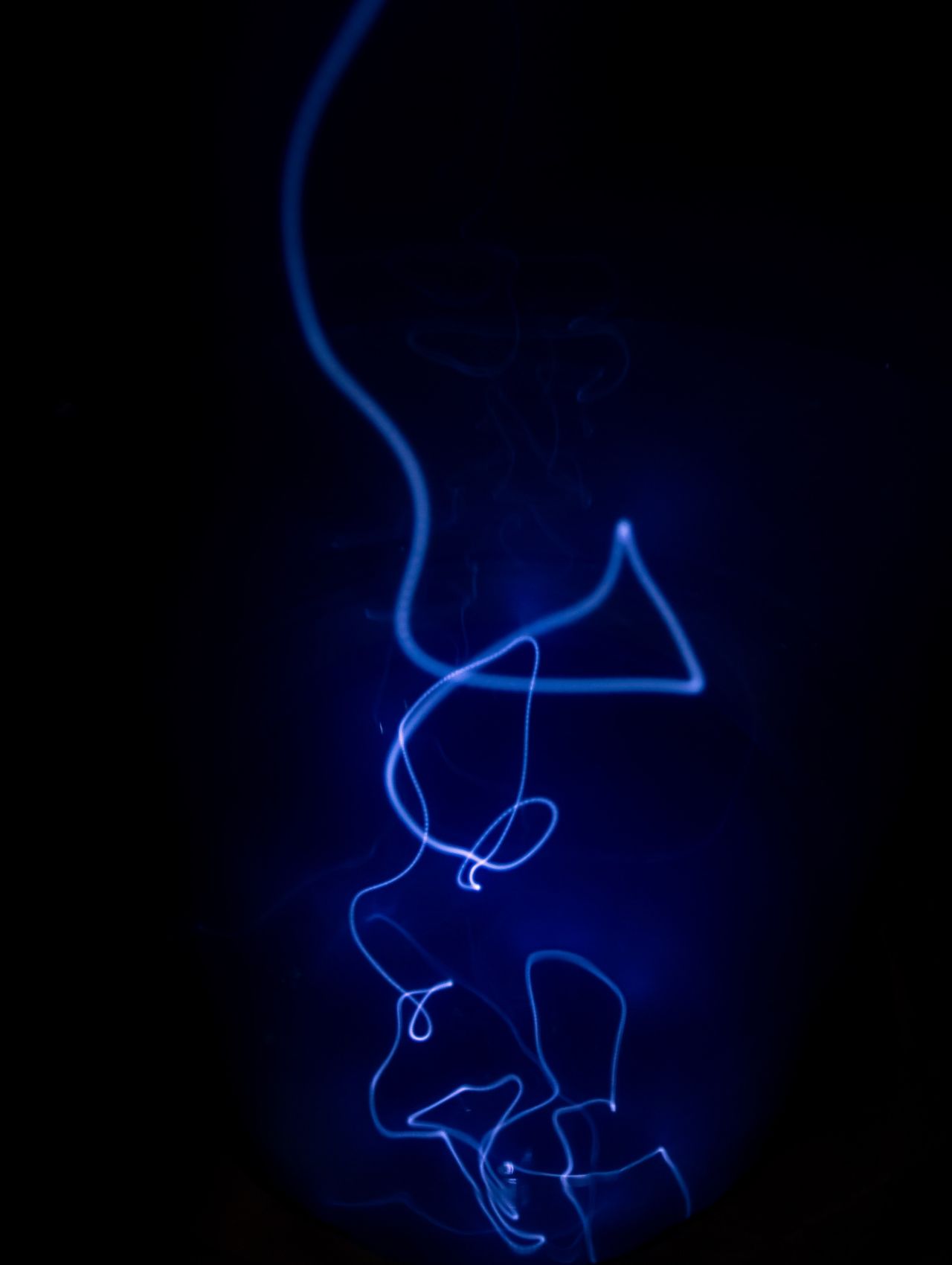 Photographie qui représente un trait de lumière bleue sur un fond noir.