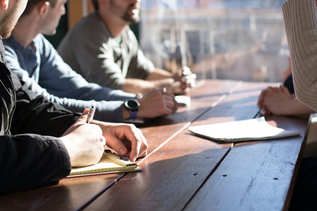 Photographie qui représente des personnes accoudées à une table et qui prennent des notes, afin d'illustrer les partenaires associés à la formation CPA.